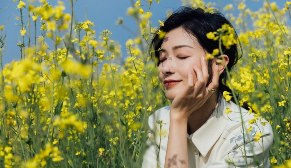 万茜晒照承包油菜花田穿白衣浅笑温柔迷人