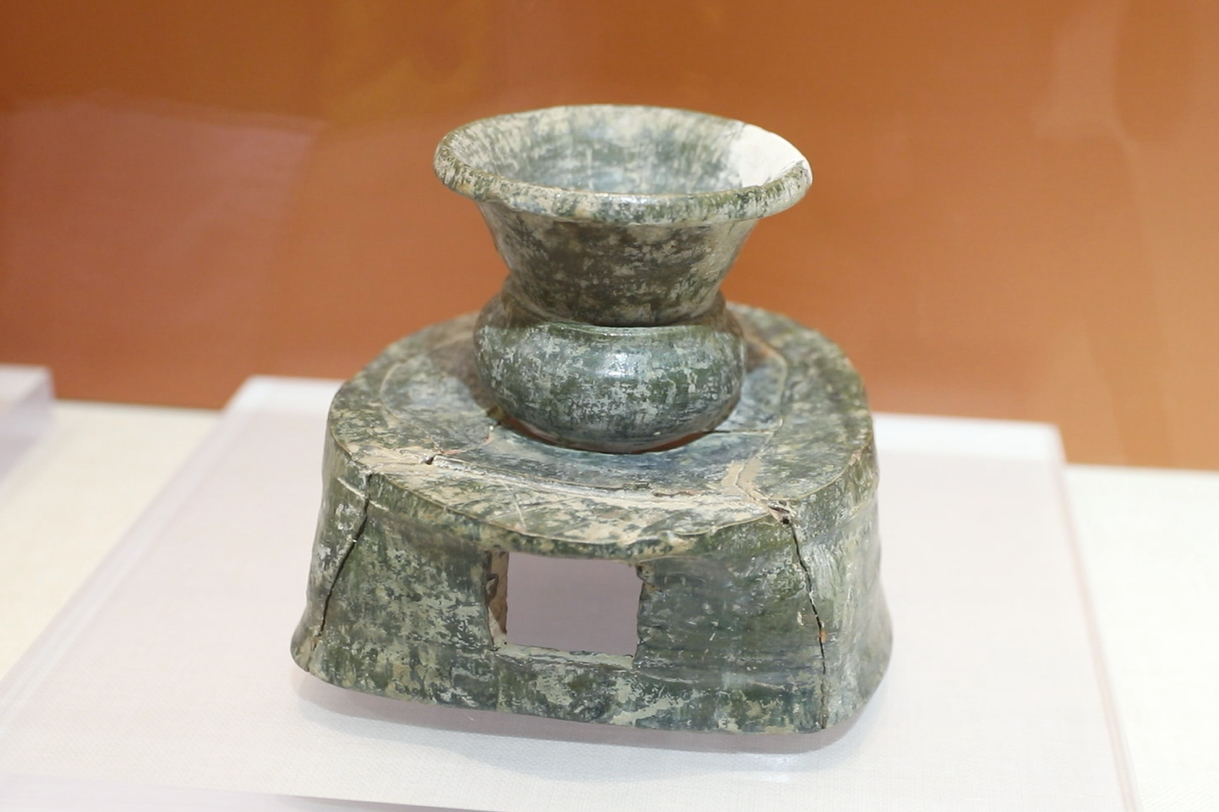 绿釉陶灶前方后圆,平面呈圆形,灶体宽短,灶面正中,有一火眼,上面放的
